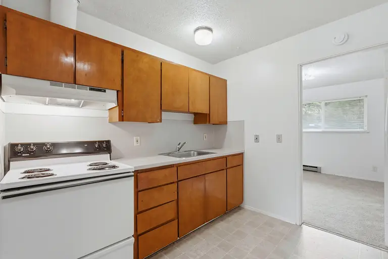 Kitchen with wood cabinets, electric range and a view into the bedroom